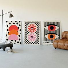 three abstract paintings hang on the wall next to a leather chair