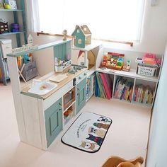 a child's play kitchen with toys and books on the shelves in front of it