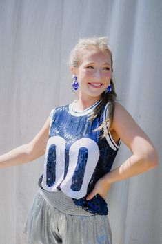 Make a statement and show your team pride with this dazzling blue & white sequin sleeveless jersey! Featuring a unique “00” in white sequins, your Game Day outfit will turn heads and let everyone know you’re a fan. Perfect for Florida Fans Go Gators!! 🐊 model, Emi is wearing a size medium Casual Stretch Sequin Tank Top, Blue Sleeveless Sports Season Tops, Blue Sleeveless Top For Sports Season, Summer Game Day Tank Top, Fitted Sleeveless Team Spirit Tops, Fitted Sleeveless Top For Team Spirit, Stretch Tops With School Spirit For Summer, White Stretch School Spirit Top, White Stretch Tops For Game Day