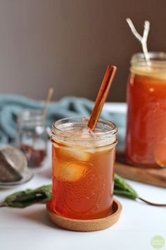 two jars filled with liquid sitting on top of a wooden tray next to spoons