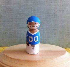 a small wooden toy with a football player on it's body and helmet, sitting on top of a table