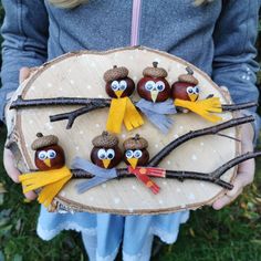 a person holding a piece of wood decorated with owls and acorns on it