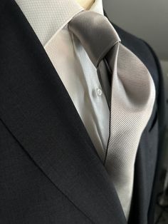 Solid ties are beautifully paired with the more busy of patters of bold stripes and heavy plaids. However, there is something so understated and elegant about a solid tie with a solid suit. Whether that be navy, charcoal or black a silver tie fits well with a white shirt and even a navy blazer with jeans. Silver necktie can also be used with formal wear. Elegant Business Suits, Tailored Suits With Standard Tie For Office, Elegant Tailored Ties For Business, Elegant Ties For Work, Elegant Solid Color Ties For Work, Tailored Elegant Ties For Business, Classic Fitted Ties For Formal Occasions, Classic Formal Suit And Standard Tie Accessories, Semi-formal Tailored Suit And Tie Accessories