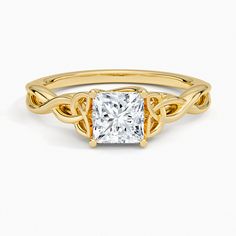 a yellow gold ring with a princess cut diamond in the center and an intricate knot around it