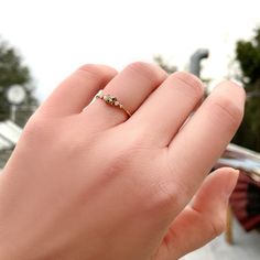 a woman's hand with a gold ring on it and an umbrella in the background