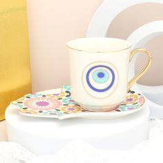 a coffee cup and saucer sitting on a plate next to a gold gift bag