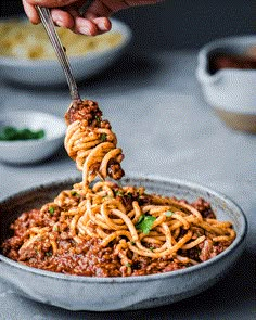 a fork full of spaghetti being lifted from a bowl