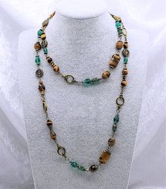 Necklace with matching set of earrings combining an elegant design approach with ethnic motifs, femininity and emancipation. The set is made with bronze findings and natural Tiger's Eye stone(10 & 8mm) beads and Green Crystal Glass beads. Necklace length: 98cm/38.5in Beautiful and attractive necklace make you charmer and elegant. Wonderful gift for you and your female friends. All of my jewellery is handmade, by me.  Every item is made personally with each one taking several hours of painstaking work.  Each item is made carefully with great attention to detail to ensure the highest possible quality. Please have a look at the other items I have for sale in my Etsy Shop or my own website larajolycraft.com Feel free to contact me at any time if you have questions. Should you buy my jewellery, Ethnic Motifs, Tiger Eye Jewelry, 8mm Beads, Seashell Jewelry, Hippie Necklace, Chakra Jewelry, Set Necklace, Teardrop Necklace, Earrings Unique