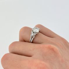 a woman's hand with a diamond ring on top of her finger, against a white background