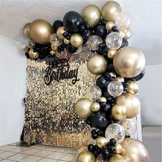 black, gold and white balloons are arranged on the floor