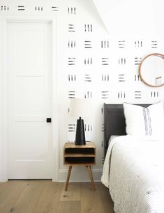 a white bedroom with black and white wallpaper