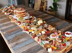 a long wooden table topped with lots of different types of cakes and desserts on top of it