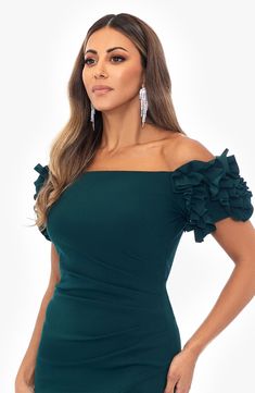 a woman wearing a green dress with ruffles on the shoulders and shoulder, posing for