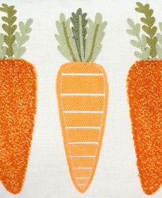 three carrots on a white pillow with green stems in the middle and orange tops