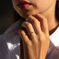 a close up of a person with a ring on their finger and wearing a white shirt