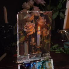 a candle is lit in an art box with flowers