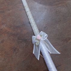 a white flower and ribbon on a long, satin - wrapped bridals stick