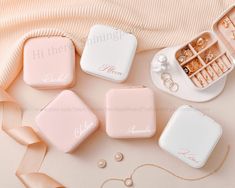 four pink and white jewelry boxes with personalized names on them next to some pearls