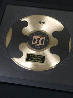 an award plaque is displayed in a black and gold frame with a circular design on it