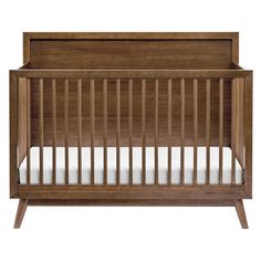 a wooden crib with white sheets on the bottom and sides, against a white background