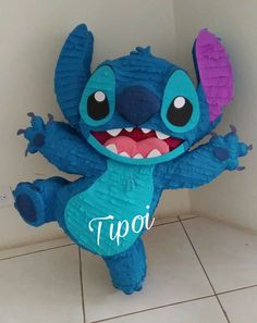 a blue stuffed animal with big teeth standing on its hind legs and arms out in the air