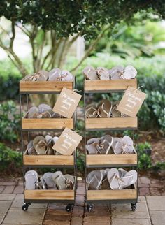 two wooden crates filled with baby shoes on top of a stone floor next to trees