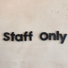 a sign that says staff only on the side of a white wall with black letters