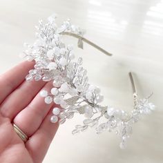 a hand is holding a tiara with pearls and crystal beads on the headband