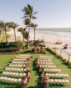 an outdoor ceremony set up on the beach with white chairs and flowers in the grass