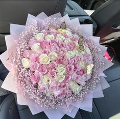 a bouquet of pink and white roses in the back seat of a car