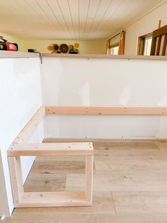 an empty room with white walls and wood flooring on one side, two shelves in the other