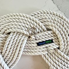 a white rope with two silver rings on it and a black tag hanging from the end