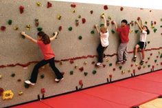 children climbing on the wall at an indoor climbing gym with their hands in the air