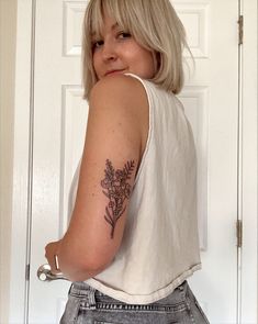 a woman with a flower tattoo on her arm, standing in front of a door