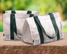 two white and green bags sitting on top of a wooden table next to each other