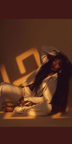 a woman laying on the ground with her legs crossed and wearing a white shirt and pants