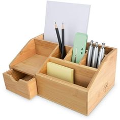 a wooden desk organizer with pens, pencils and paper in it on a white background