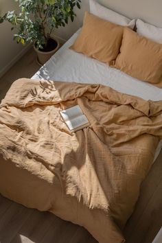 an unmade bed with two pillows and a book on it