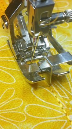 an old sewing machine is sitting on a yellow and white tablecloth with floral designs