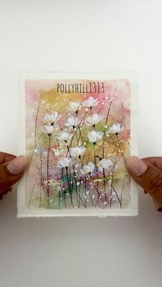 two hands holding up a small card with flowers on it and the words polyhilia above them