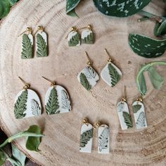 the earrings are made out of ceramic and have green leaves on them, along with gold earwires