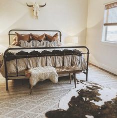 a bed room with a neatly made bed and a cow skull mounted on the wall