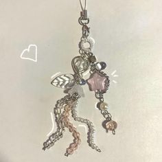 a keychain with charms attached to it on a white surface and a heart in the background