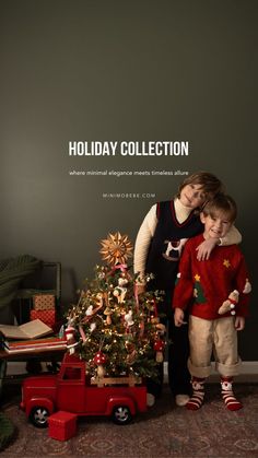 two children standing in front of a christmas tree