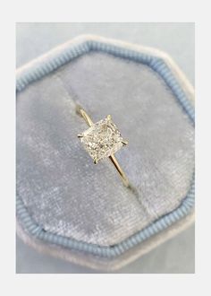 a diamond ring sitting on top of a blue velvet bag