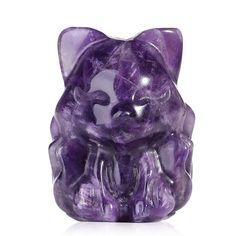 a purple glass cat figurine sitting on top of a white surface with its eyes closed