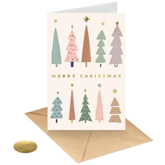 a card with christmas trees on it and a cookie next to the card, which says merry christmas