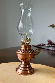 an old fashioned oil lamp sitting on top of a wooden table