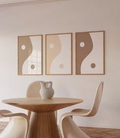 a white vase sitting on top of a wooden table next to two framed pictures above it