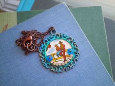 This handmade necklace features a vintage country-western cowboy scene upcycled from a vintage 1950s card game! The image is sealed with layers of clear varnish.I added a band of rhinestones with a blue flower cabochon on each side for a pop of whimsical glam.The hand-painted filigree pendant hangs on a new antiqued coper chain that is lead/nickel/tarnish free. You select the chain length option that fits best.A perfect anytime/anywhere kitschy statement necklace to keep or give to someone aweso Handmade Vintage Necklace For Western-themed Events, Vintage Handmade Necklace For Western-themed Events, Blue Western Style Concho Necklace, Western Blue Concho Necklace, Cowboy Necklaces, Cowboy Scene, Vintage Cowboys, Cowboy Boot Pendant, Ranch Cowboy